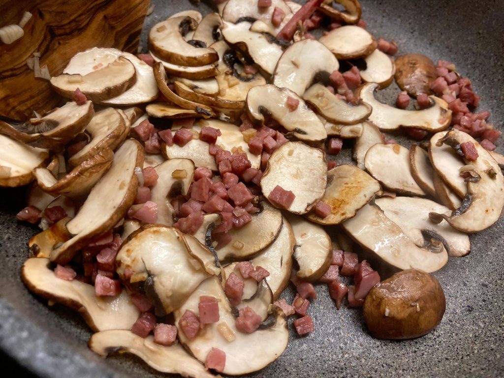 Champignons und Schinkenwürfel trocken anbraten