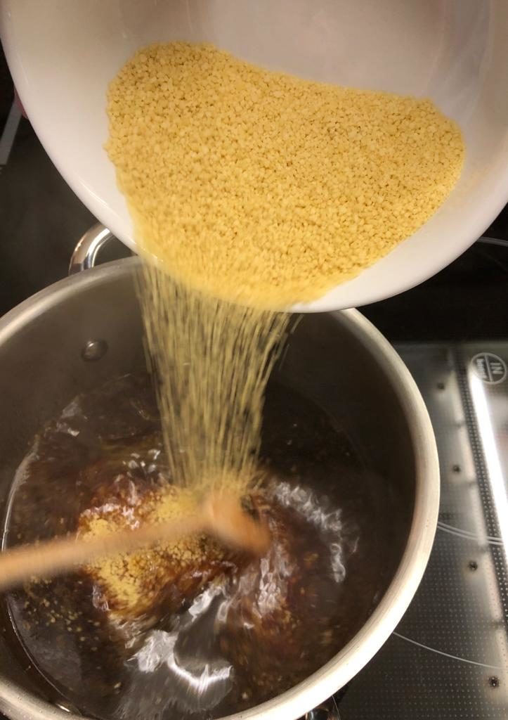 Couscous in den Bratensaft des Maishähnchens geben