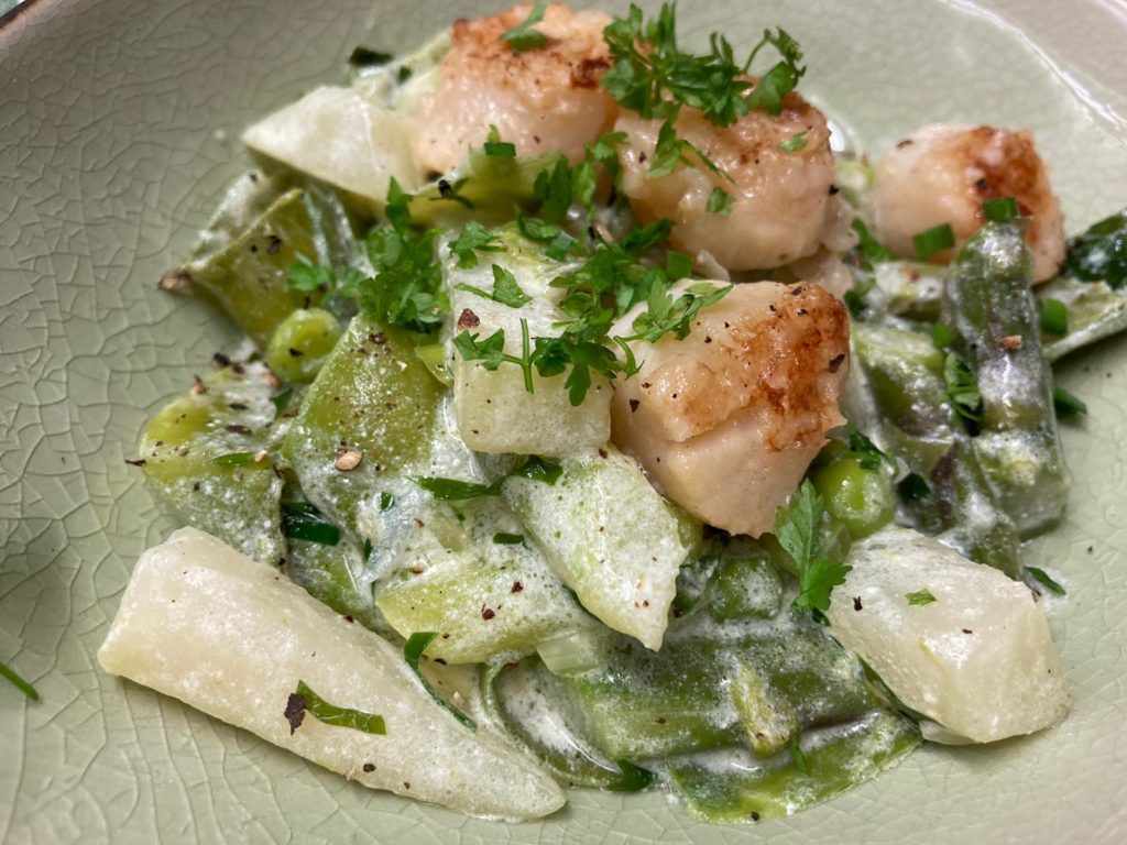 Jakobsmuscheln mit Erbsen, Kohlrabi und grünem Spargel im Teller