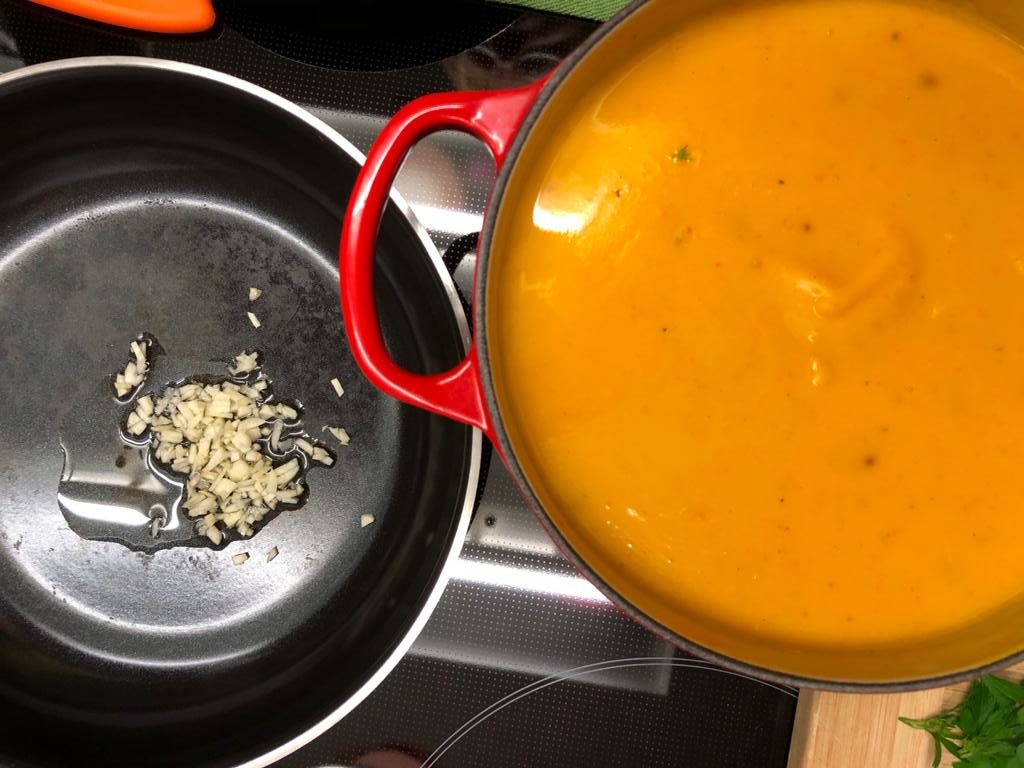 Kürbissuppe und in Öl schwitzender Knoblauch