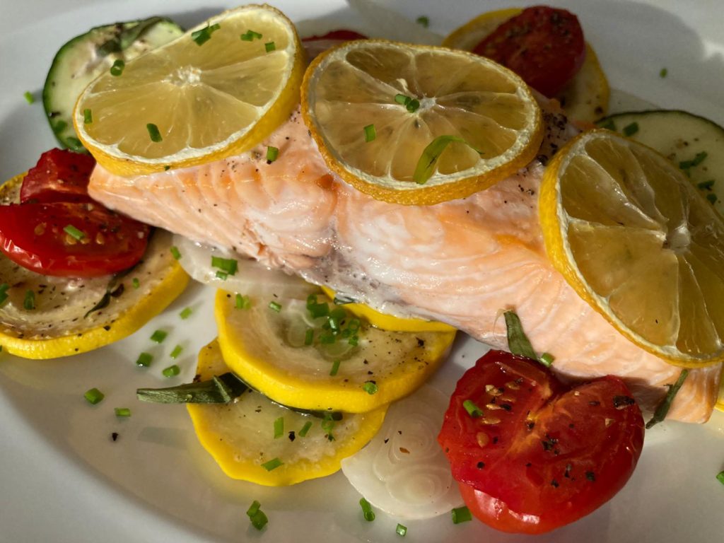 Lachs mit Zucchini-Zwiebel-Gemüse aus dem Backofen im Teller