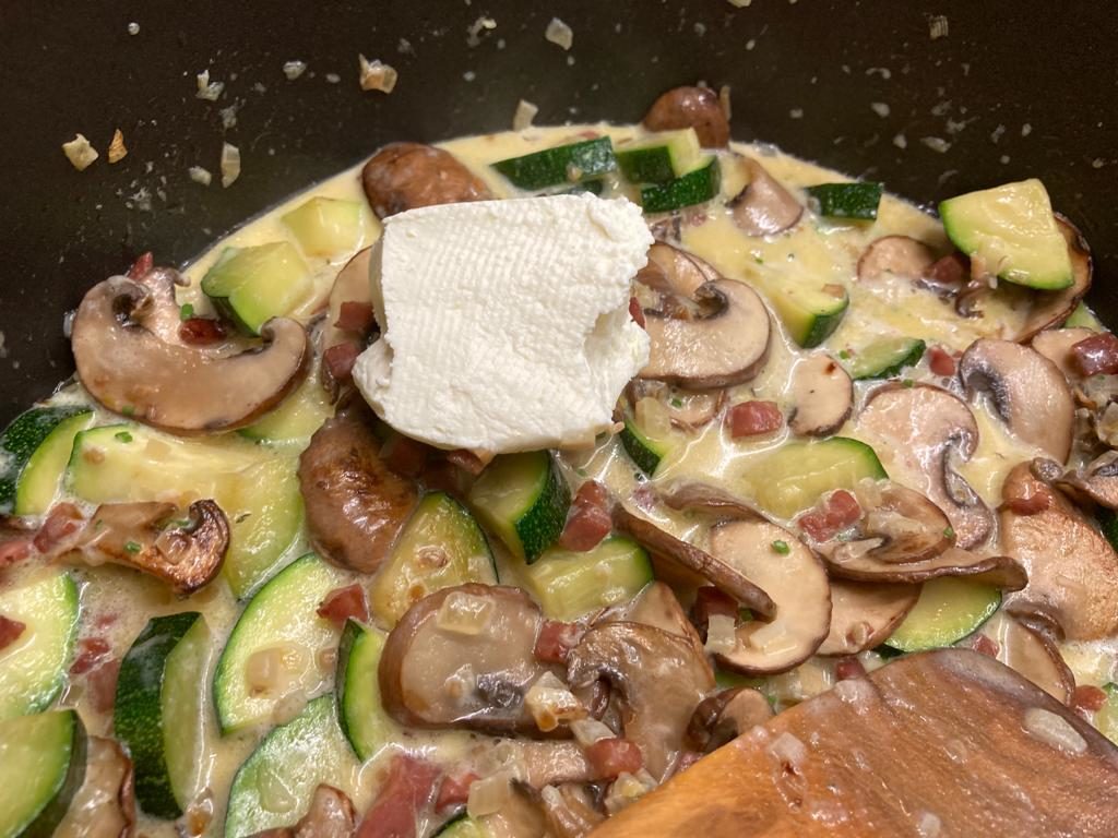 Sahne und Frischkäse zu den Zucchini geben