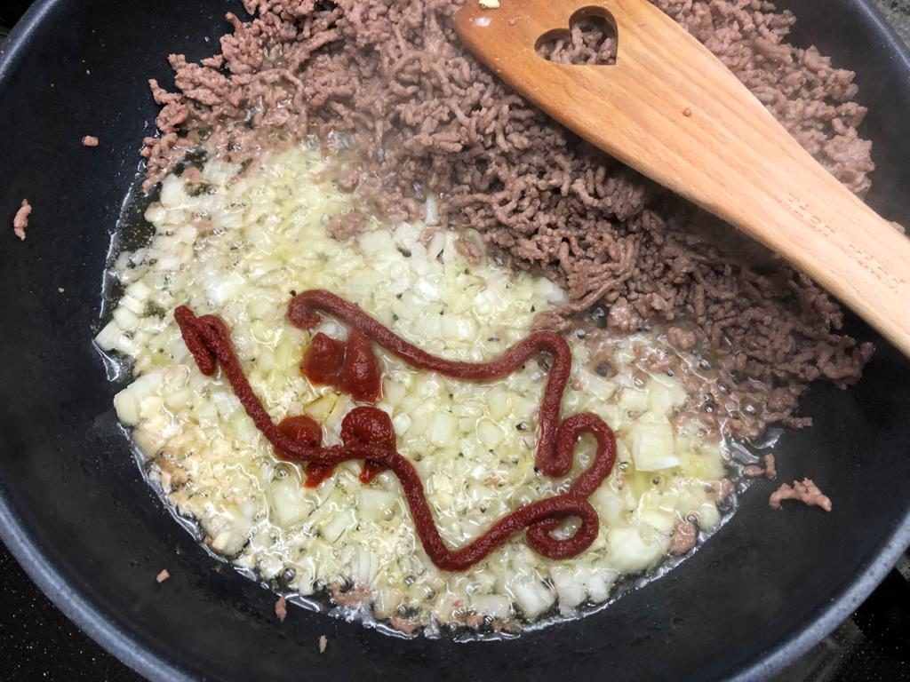 Zwiebeln und Tomatenmark - mit etwas Zucker - zum Hack geben